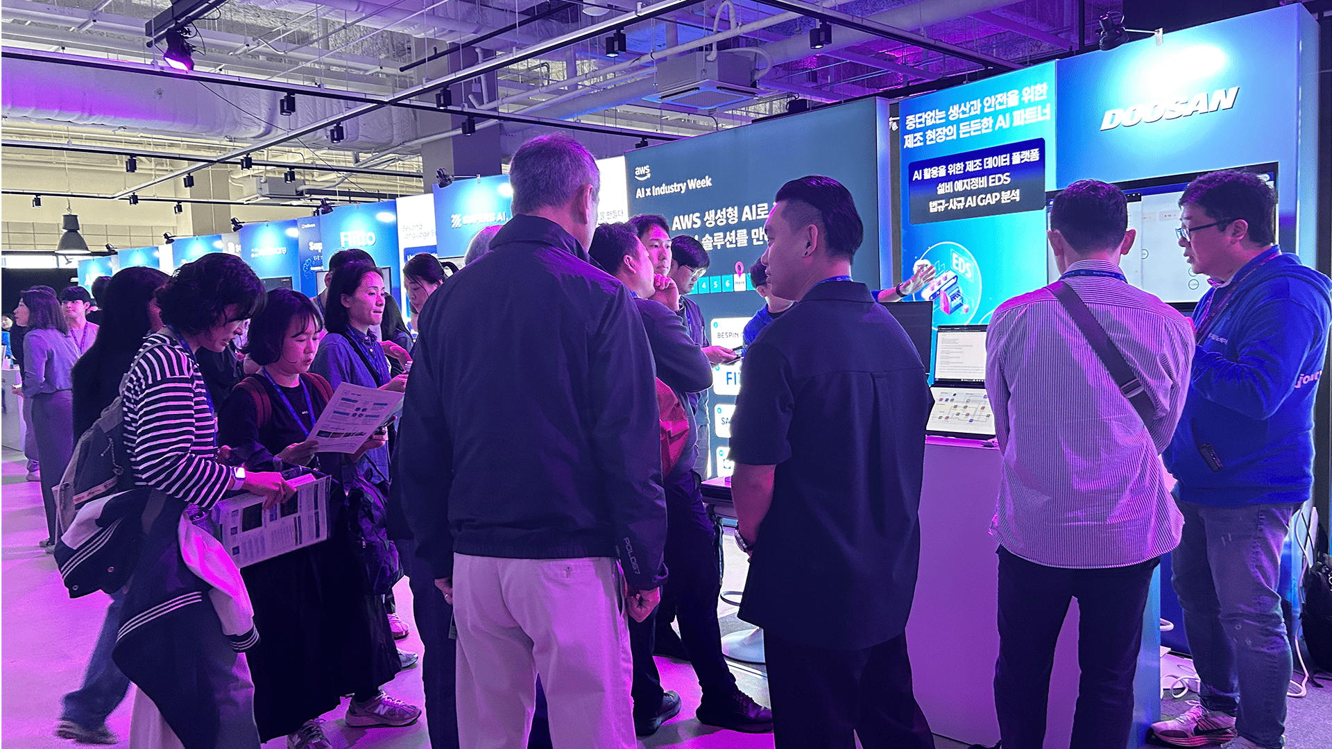 AWS AI x Industry Week 2025 현장에서 제조 AI 혁신 솔루션을 체험하는 참관객들로 붐비는 (주)두산디지털이노베이션BU 부스